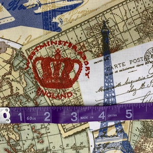 May include: Fabric with a vintage travel theme. The design includes maps, a red crown, the Eiffel Tower, and a postcard. A purple measuring tape shows 60 inches. The fabric has a cream background with blue and brown accents.