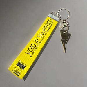 Yellow wristlet keychain for keys  with the words "Void If Tampered"