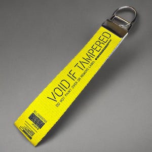 Yellow wristlet keychain for keys  with the words "Void If Tampered"