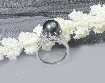 Könnte beinhalten: Ein silberner Ring mit einem schwarzen Perlmutt, das in einem zarten, floralen Design eingefasst ist.