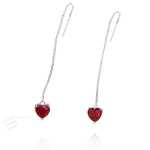 Może przedstawiać: Para srebrnych kolczyków wiszących w kolorze srebrnym. Każdy kolczyk ma mały, czerwony kamień szlachetny w kształcie serca zawieszony na delikatnym łańcuszku. Kolczyki są przeznaczone do przeciągania przez ucho.