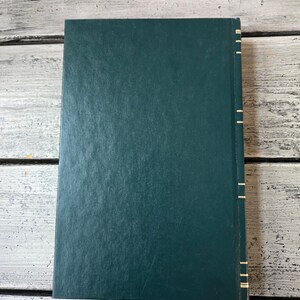 May include: A dark green hardback book with gold accents along the spine.