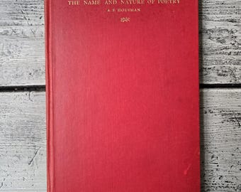 May include: A red hardcover book with the title "The Name and Nature of Poetry" by A.E. Housman.