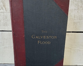 May include: An antique book titled "The Galveston Flood." The book has a dark gray cover with burgundy accents on the spine and corners. The title is in gold lettering.