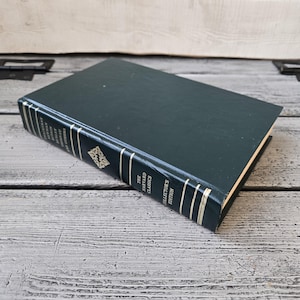 May include: A dark green hardcover book titled "The Harvard Classics Collectors Edition" with gold lettering and a decorative emblem. The book is resting on a weathered, light gray wooden surface.