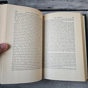 May include: A close-up of an open book with a green cover. The pages are yellowed with age and the text is printed in black. The book is titled "Ralph Waldo Emerson" and the chapter is titled "The Over-Soul".