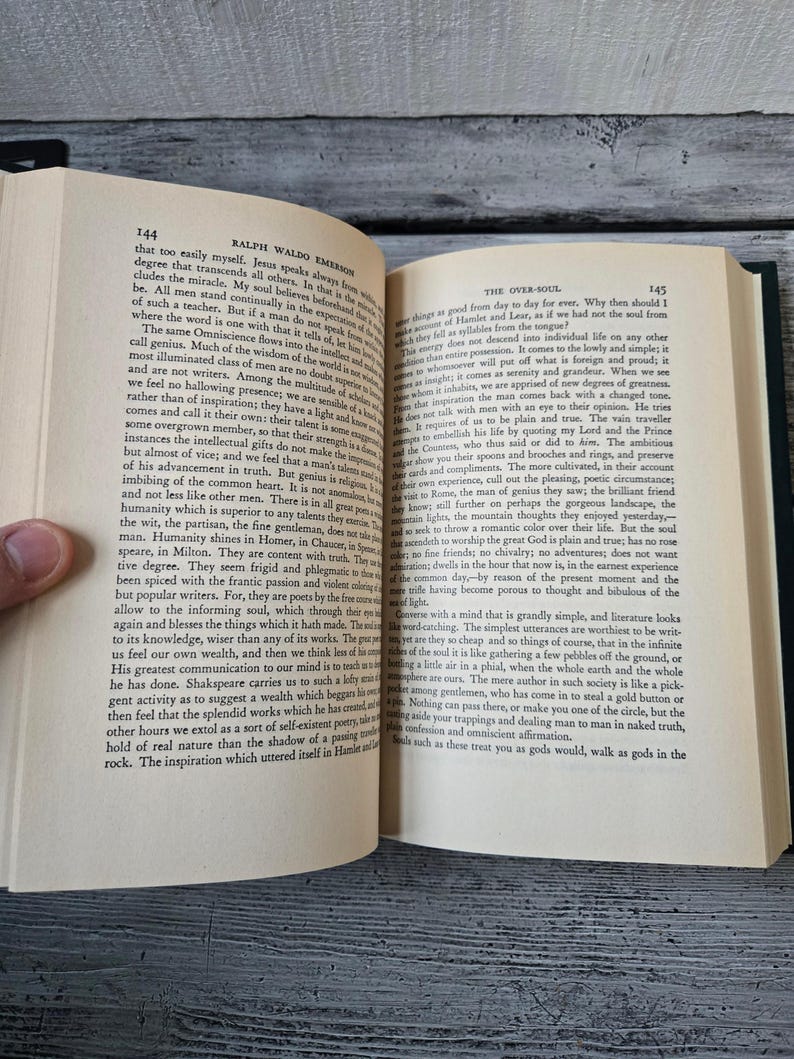 May include: A close-up of an open book with a green cover. The pages are yellowed with age and the text is printed in black. The book is titled "Ralph Waldo Emerson" and the chapter is titled "The Over-Soul".