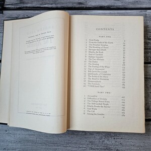 May include: An open book with a white cover and pages, displaying the contents of a book. The text includes chapter titles like "First Fruits" and "The Zealot." The book is on a wooden surface.
