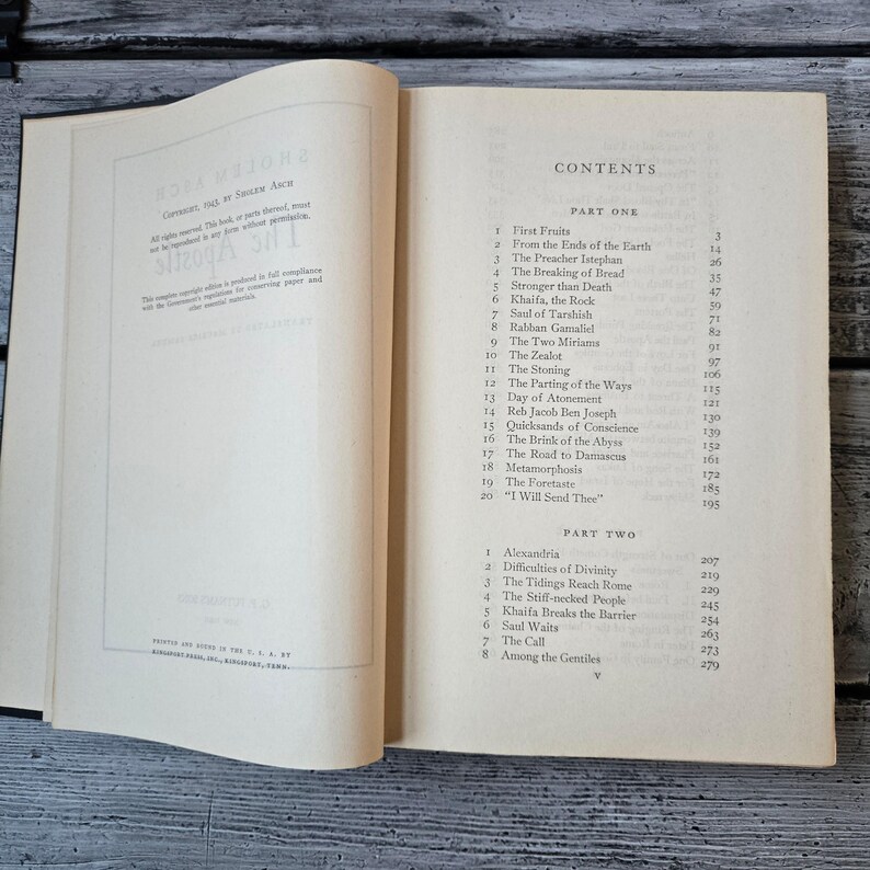 May include: An open book with a white cover and pages, displaying the contents of a book. The text includes chapter titles like "First Fruits" and "The Zealot." The book is on a wooden surface.