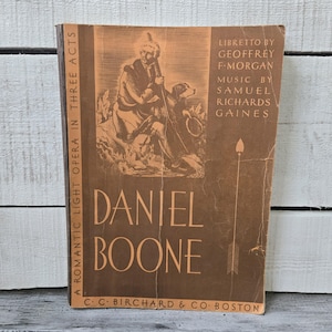 May include: A vintage book cover in shades of brown features the title "DANIEL BOONE" in large letters. The cover includes an illustration of a man with a dog, and text indicating it's a romantic light opera. The publisher's name is also visible.