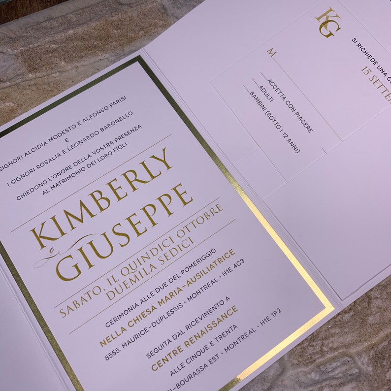 May include: A white wedding invitation with gold accents. The invitation features the names Kimberly and Giuseppe, the date Saturday, October 15, 2016, and the time 2:00 PM. The invitation also includes the location of the ceremony and reception.