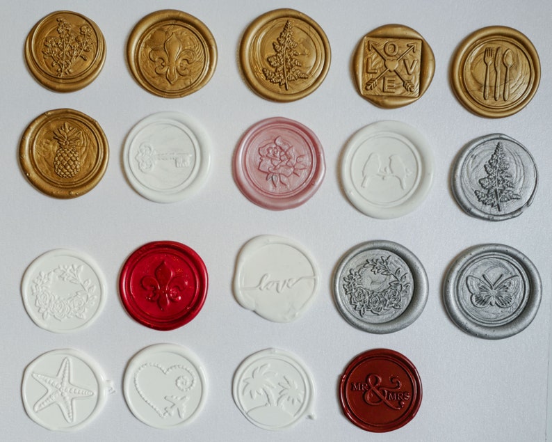 May include: Assortment of 18 wax seals with various designs, including floral, geometric, and abstract patterns. The seals are in gold, silver, red, white, and pink.