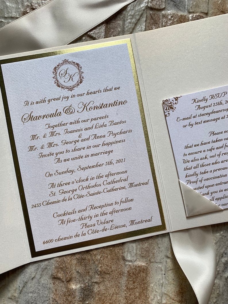 May include: A white and gold wedding invitation with a gold ribbon. The invitation features the couple's names, "Stavroula & Konstantino", the date of the wedding, "September 5th, 2021", and the location of the ceremony and reception. The invitation also includes a RSVP card with the couple's contact information.
