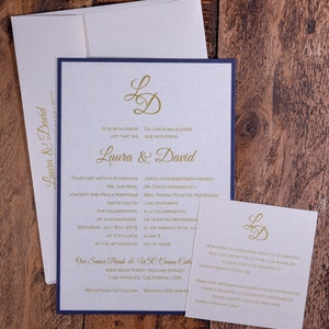 May include: A wedding invitation with a navy blue border and gold lettering. The invitation is for Laura and David and includes the date, time, and location of the wedding. The invitation also includes the text "It is with great joy that we..." and "Es con suma alegr&iacute;a que nosotros..."