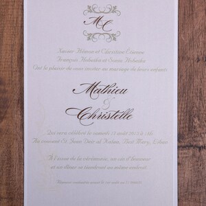 May include: Ivory wedding invitation with brown script and decorative flourishes. The invitation includes the names Mathieu and Christelle, along with event details. The text is in French, with the date of the wedding and location.