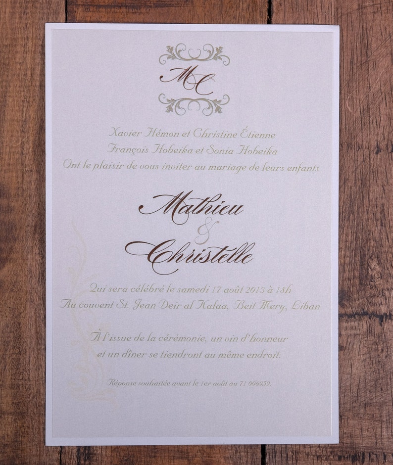 May include: Ivory wedding invitation with brown script and decorative flourishes. The invitation includes the names Mathieu and Christelle, along with event details. The text is in French, with the date of the wedding and location.