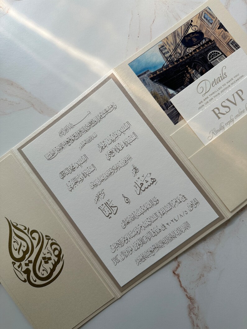 May include: A white and gold wedding invitation with Arabic calligraphy and a photo of a building. The invitation includes the names of the couple, the date and time of the wedding, and the location. The RSVP details are on a separate card.
