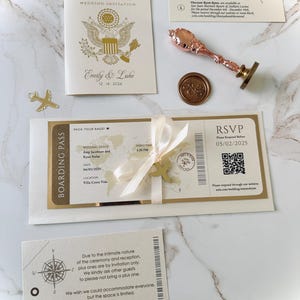 Billet d'embarquement avec bordure en feuille d'or, invitation à destination enveloppée dans un ruban et avion en acrylique doré, invitation à voyager sur une carte du monde