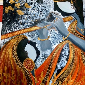 May include: A painting of two figures in profile, one playing a flute. The figures are dressed in orange and gold garments with intricate patterns. The background is a dark gray with white and gold accents.