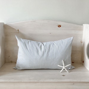 May include: A white wooden bench with a blue and white striped pillow and a white starfish on the seat.