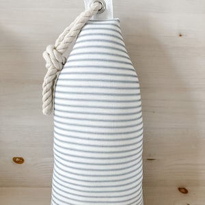 May include: A white and blue striped fabric doorstop with a rope handle and a metal eyelet.