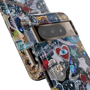 May include: A black phone case with a colourful, glittery design featuring hearts, stars, and other embellishments. The case has a gold trim and a camera lens cover.