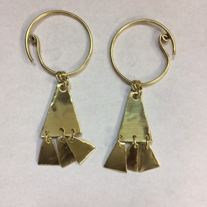 May include: A pair of gold hoop earrings with a dangling triangle charm. The triangle charm has three smaller triangles hanging from it.