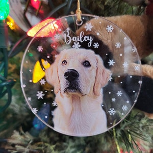Clear Round Acrylic Christmas ornament with a photo of a dog and name with snow flakes background.