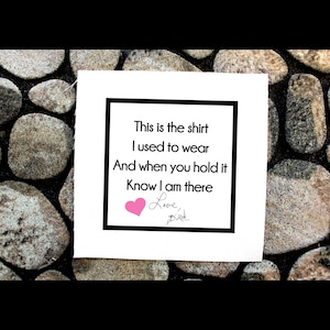 Peut inclure: Une carte blanche avec du texte noir et un cœur rose. Le texte dit "This is the shirt I used to wear And when you hold it Know I am there Love,"