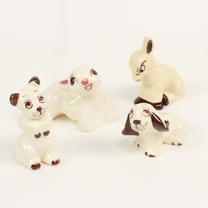 May include: Set of four ceramic animal figurines. The figurines are white with brown accents and feature a dog, a rabbit, a lamb, and a donkey.