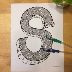 May include: A black and white printable coloring page featuring a detailed illustration of the letter S. The letter is filled with small circles and dots.