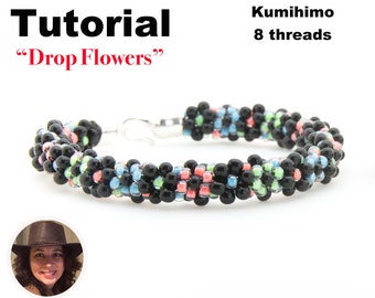 May include: A black and multi-colored beaded bracelet with a silver clasp. The bracelet is made using the Kumihimo technique with 8 threads. The bracelet is labeled "Drop Flowers" and "Tutorial".