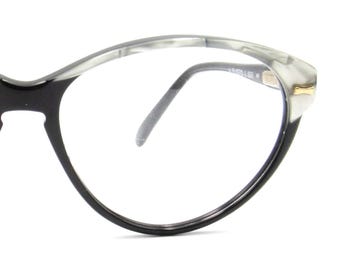 May include: Close-up of a pair of eyeglasses with a black frame and a gray and white marbled upper rim. The glasses have a gold accent on the corner and a thin, gray nose bridge.