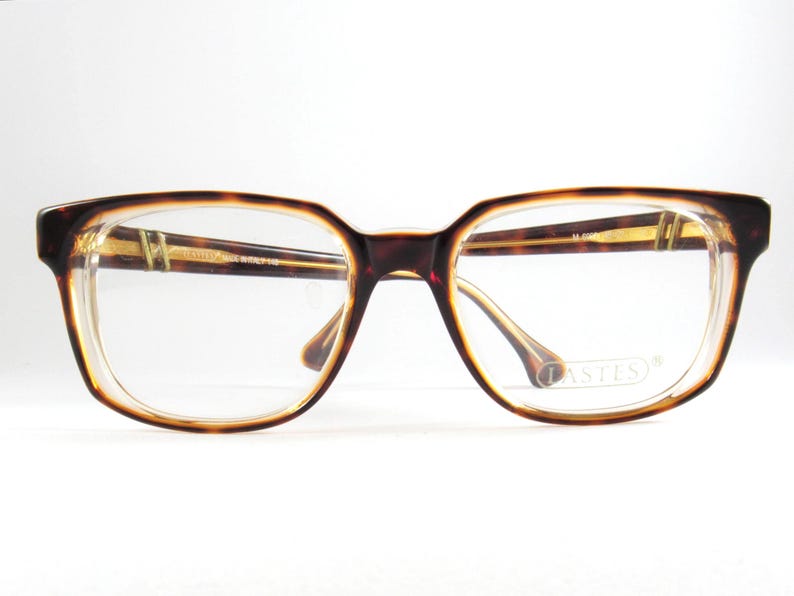May include: Rectangular eyeglasses with a tortoiseshell pattern frame. The glasses have clear lenses and a brown and gold color scheme. The brand name "LASTES" is visible on the lens. The frame is made in Italy.