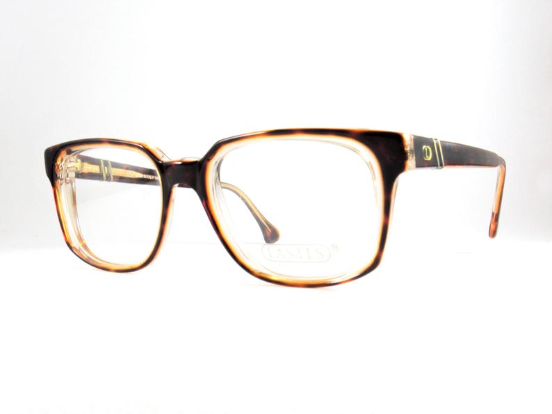 May include: Eyeglasses with a tortoiseshell pattern on the frames. The frames have a rectangular shape with rounded edges. The lenses are clear. The temples are dark brown with a gold accent. The overall style is vintage.