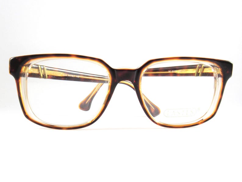 May include: Vintage eyeglasses with a tortoiseshell pattern frame. The rectangular frames have a clear lens and a brown and tan color scheme. The arms and bridge of the glasses are a light brown color. The glasses are set against a white background.
