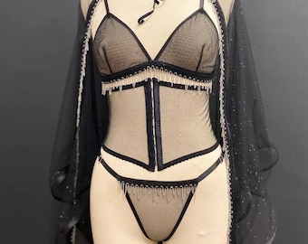 Completo intimo nero trasparente con corsetto e mantello scintillante, corsetto sottoseno da sposa e perizoma in tulle glitterato.