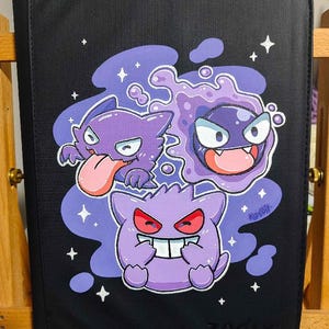 May include: A black rectangular portfolio case featuring a colorful graphic of three purple ghost-like creatures with expressive faces. The design includes white star accents and a purple cloud-like background. The brand name Zofly is embossed at the bottom.