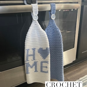 May include: Two crocheted tea towels hanging on an oven handle. One towel is white with blue lettering that says "HOME" and a blue heart. The other towel is blue. Crochet pattern.