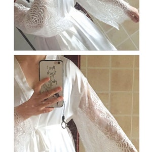 May include: White satin robe with lace trim on the sleeves. The robe has a tie belt and is shown being worn by a person.