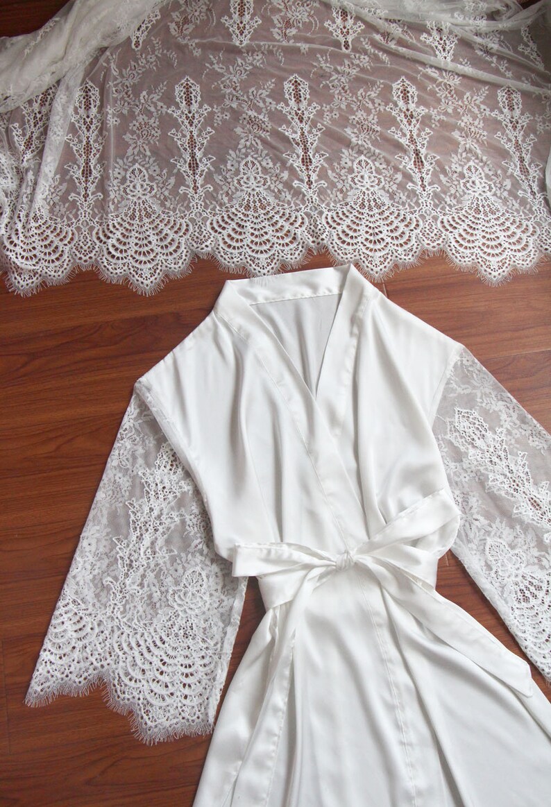May include: White satin robe with lace sleeves. The robe has a V-neck and a tie belt.