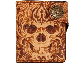 Könnte beinhalten: Eine braune Ledergeldbörse mit einem geprägten Totenkopfdesign auf der Vorderseite. Die Geldbörse hat einen Druckknopfverschluss und einen dekorativen Metallknopf.