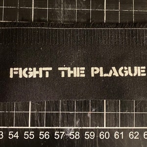 May include: Black fabric patch with white text that reads "FIGHT THE PLAGUE".