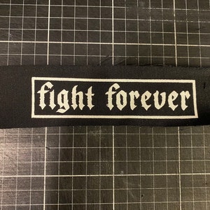 May include: Black fabric patch with white text that reads "fight forever" in a gothic font.