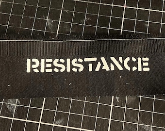 May include: Black fabric with the word "RESISTANCE" printed in white.