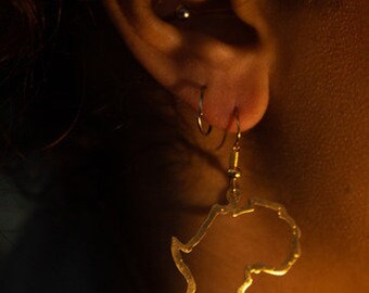 May include: Gold earring shaped like the outline of the continent of Africa.