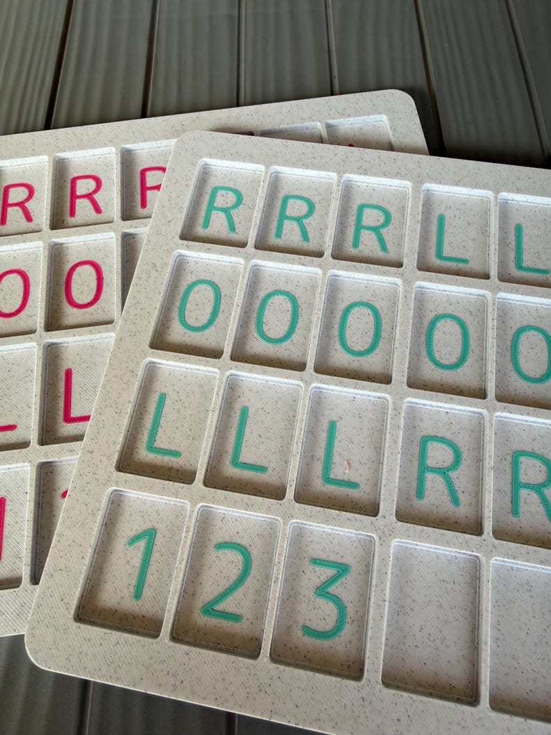 May include: Two off-white speckled plastic trays with rectangular recessed compartments. The front tray features teal letters R, L, and numbers 1, 2, 3. The back tray features pink letters R, L, and O. Each compartment is arranged in a grid pattern.