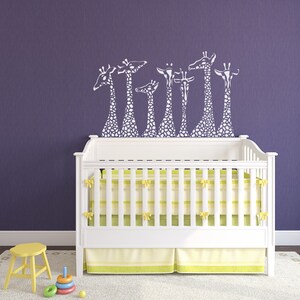May include: White crib with a yellow and green striped mattress and a white ruffle skirt. A purple wall with a white giraffe decal above the crib.