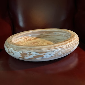 May include: A large, oval-shaped bowl with a white and brown marbled glaze. The bowl has a wide, shallow rim and a smooth, glossy finish.