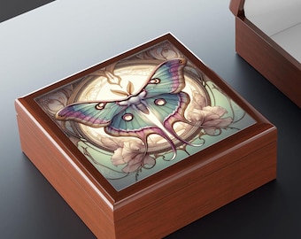 Puede incluir: Una caja de madera con una tapa con bisagras. La tapa presenta una ilustración colorida de una polilla con detalles intrincados y un diseño floral. La caja es de color marrón claro.